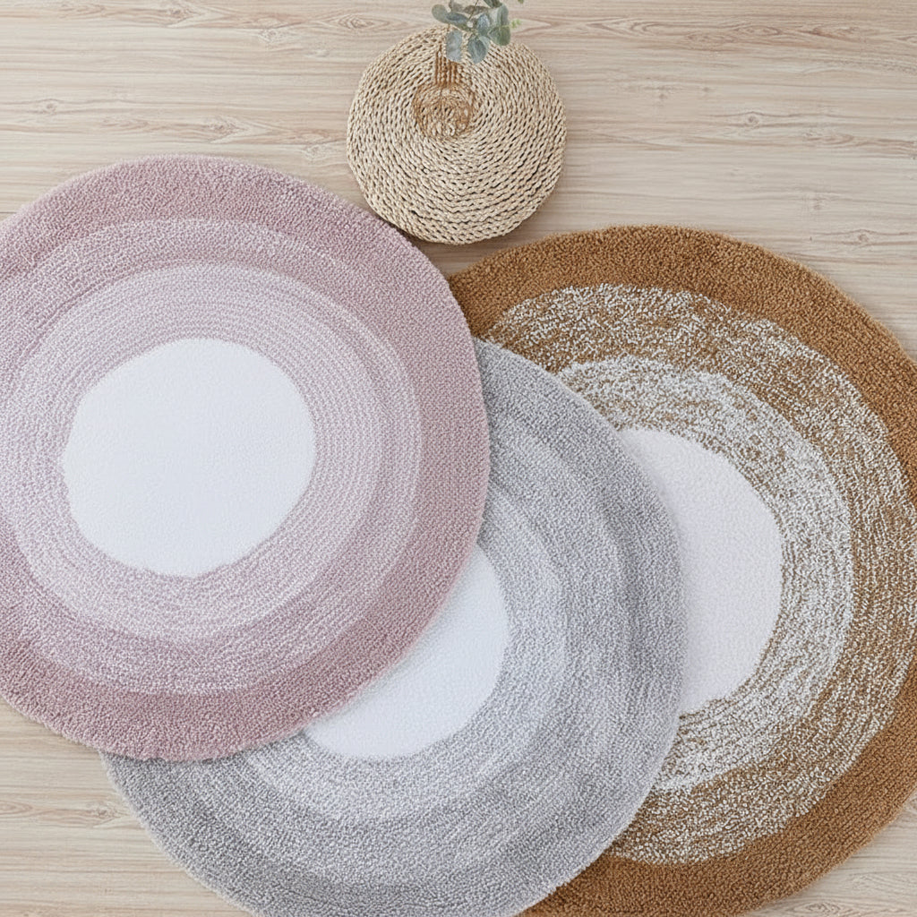 Three round rugs in pink, gray, and brown on a wooden floor.